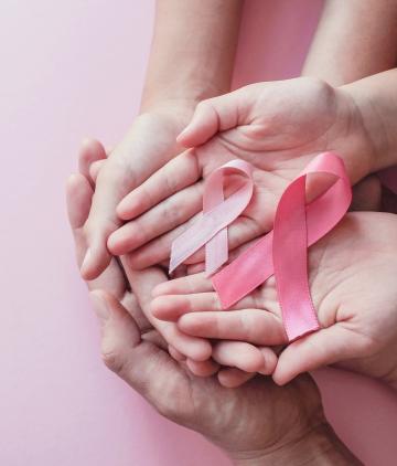 Hands holding pink ribbons