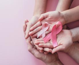 Hands holding pink ribbons